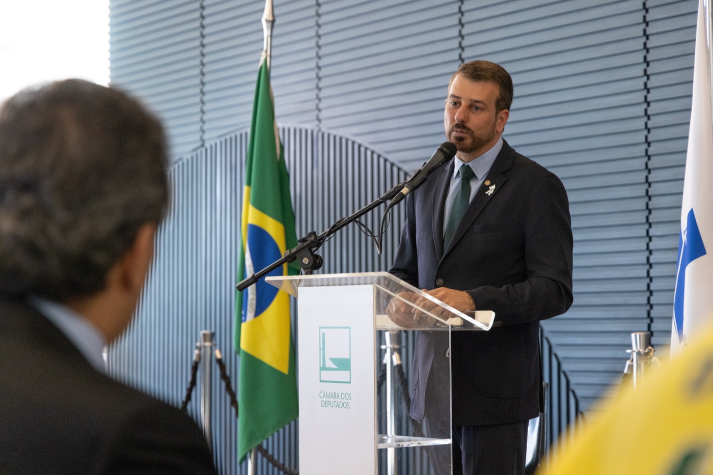 Daniel Soranz discursa em cerimônia oficial, com a bandeira do Brasil ao fundo